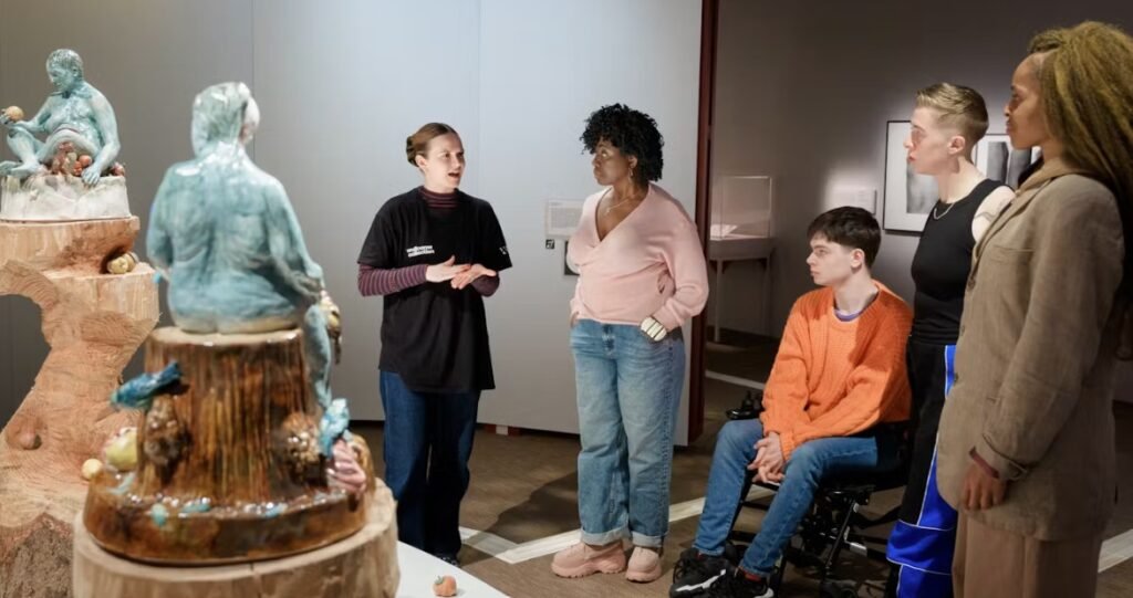 A member of staff uses hand gestures whilst giving a tour of an exhibition.